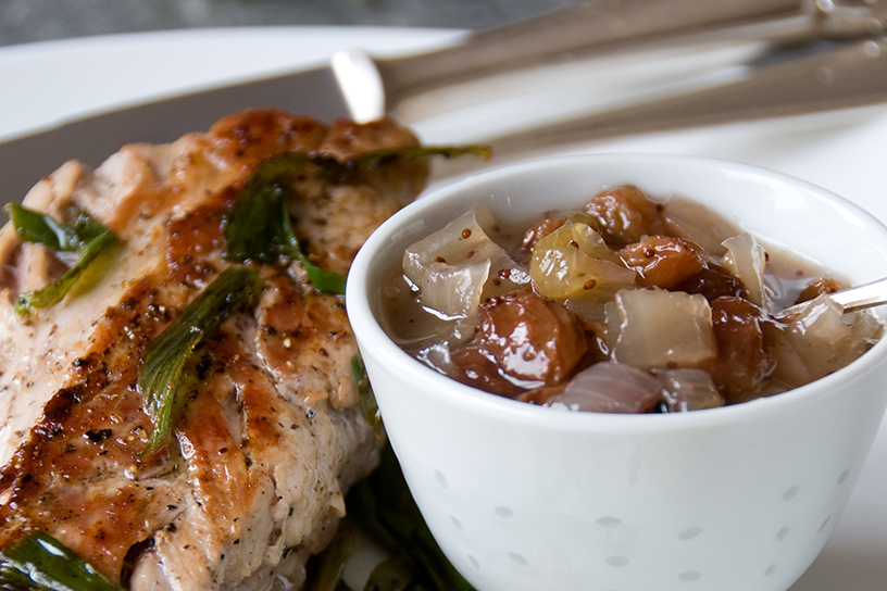 Kruisbessenrelish in een schaaltje met een stuk vlees ernaast